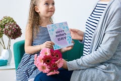 Dia feliz do `s da matriz Menina bonito que dá o cartão, o presente e o ramalhete da mamã de margaridas cor-de-rosa do gerbera Mã imagem de stock Dia feliz do `s da matriz Menina bonito que dá o cartão, o presente e o ramalhete da mamã de margaridas cor-de-rosa do gerbera Mã imagem de stock