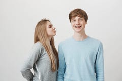 Diami il bacio già Amica bionda tenera sveglia che sta nelle punte delle dita del piede per raggiungere la guancia del ragazzo, l immagine stock libera da diritti Diami il bacio già Amica bionda tenera sveglia che sta nelle punte delle dita del piede per raggiungere la guancia del ragazzo, l immagine stock libera da diritti