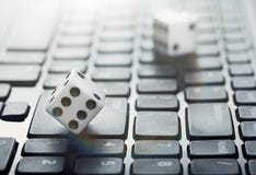 Dice on laptop computer keyboard. Сoncept of online gambling and online casino. Creative idea with devil`s bones and PC keyboard.