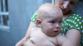 Dicht portret van een één éénjarigebaby De kindschreeuwen terwijl het zitten op zijn moeders omwikkelen De moeder kalmeert baby, stock videobeelden Dicht portret van een één éénjarigebaby De kindschreeuwen terwijl het zitten op zijn moeders omwikkelen De moeder kalmeert baby, stock videobeelden