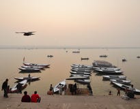 Die Boote von Varanasi mit fliegenden Unkosten des Vogels lizenzfreie stockbilder Die Boote von Varanasi mit fliegenden Unkosten des Vogels lizenzfreie stockbilder