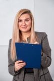 Die Geschäftsfrau, die mit Ausschnittsbrett im Büro steht und bereiten vor, um etwas zu schreiben stockfotos Die Geschäftsfrau, die mit Ausschnittsbrett im Büro steht und bereiten vor, um etwas zu schreiben stockfotos