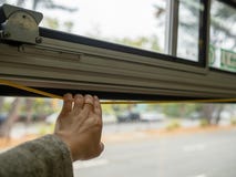 Die Hand der Frau, die eine gelbe Buszugschnur mit Stadt in der Rückseite zieht lizenzfreie stockfotografie Die Hand der Frau, die eine gelbe Buszugschnur mit Stadt in der Rückseite zieht lizenzfreie stockfotografie
