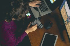 Die hintere Ansicht des jungen Fotografen betrachtend machte die Fotos in camera, die auf Arbeitsplatz mit modernen Geräten f sit lizenzfreie stockfotografie Die hintere Ansicht des jungen Fotografen betrachtend machte die Fotos in camera, die auf Arbeitsplatz mit modernen Geräten f sit lizenzfreie stockfotografie