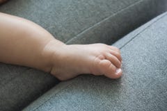 Die Hände der Mutter und die Füße des Babys auf einem grauen Sofa lizenzfreie stockfotos Die Hände der Mutter und die Füße des Babys auf einem grauen Sofa lizenzfreie stockfotos