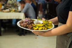 Die Kellnerin trägt eine Platte von Kartoffeln und von Kebabs dient einen Bankettisch stockfoto Die Kellnerin trägt eine Platte von Kartoffeln und von Kebabs dient einen Bankettisch stockfoto