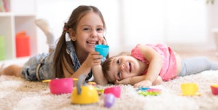 Die netten lustigen Kinder, die mit Dishware spielen, spielt zu Hause stockbilder Die netten lustigen Kinder, die mit Dishware spielen, spielt zu Hause stockbilder
