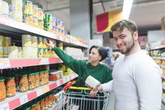 Die Schönheit eines jungen Paares kauft eingemachtes Gemüse in einem Supermarkt Porträt eines lächelnden Mannes in einem Supermar stockfotos Die Schönheit eines jungen Paares kauft eingemachtes Gemüse in einem Supermarkt Porträt eines lächelnden Mannes in einem Supermar stockfotos