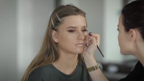 Die zukünftige Braut kam zu einem Schönheitssalon zum Make-upkünstler auf dem Make-uptest Mädchen, das im netten Lächeln des Raum stock video footage Die zukünftige Braut kam zu einem Schönheitssalon zum Make-upkünstler auf dem Make-uptest Mädchen, das im netten Lächeln des Raum stock video footage