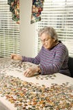 Die ältere Frau, die Spannvorrichtung tut, sah Puzzlespiel stockbild Die ältere Frau, die Spannvorrichtung tut, sah Puzzlespiel stockbild