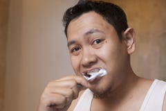 Dientes que aplican con brocha del hombre en cuarto de ba?o imagen de archivo Dientes que aplican con brocha del hombre en cuarto de ba?o imagen de archivo