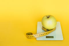 Diet concept. Apples and table top kitchen scales and measuring tape line on yellow background. royalty free stock photography Diet concept. Apples and table top kitchen scales and measuring tape line on yellow background. royalty free stock photography