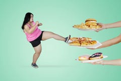 Obese woman kicking unhealthy foods stock photography Obese woman kicking unhealthy foods stock photography