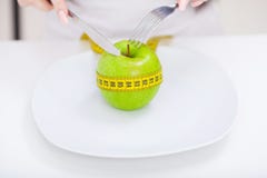 Dieta Chiuda sulla foto della misura di nastro arrotolata intorno ad una mela su w fotografie stock Dieta Chiuda sulla foto della misura di nastro arrotolata intorno ad una mela su w fotografie stock