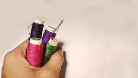 Different colours thread rolls with needle in hand of a tailor. royalty free stock image Different colours thread rolls with needle in hand of a tailor. royalty free stock image