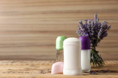 Different female deodorants and lavender flowers on wooden background, space for text