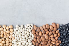 Different kinds of beans: black, pinto, white and chickpeas, on a concrete background, copy space, horizontal stock photo Different kinds of beans: black, pinto, white and chickpeas, on a concrete background, copy space, horizontal stock photo