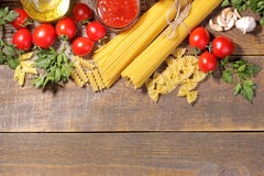 Different types of pasta with cherry tomatoes, olive oil, parsley on a brown wooden background. royalty free stock photography Different types of pasta with cherry tomatoes, olive oil, parsley on a brown wooden background. royalty free stock photography
