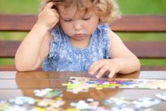 Difficult task. Tired child playing jigsaw with serious face. stock photos Difficult task. Tired child playing jigsaw with serious face. stock photos