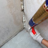 Difficulté de la main du travailleur un loyer dans le mur utilisant la mousse de polyuréthane image stock Difficulté de la main du travailleur un loyer dans le mur utilisant la mousse de polyuréthane image stock