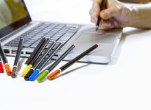 Digitas ou artes gráficas tradicionais? A mão de uma mulher parece tirar na almofada de toque de um laptop com lotes do colorido fotografia de stock royalty free Digitas ou artes gráficas tradicionais? A mão de uma mulher parece tirar na almofada de toque de um laptop com lotes do colorido fotografia de stock royalty free