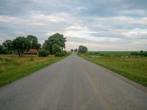 Direct asphalt road through the countryside under the sky, on which the clouds float stock photos Direct asphalt road through the countryside under the sky, on which the clouds float stock photos