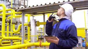 Dirija sostener una tableta, hablar en el Walkietalkie y la sonrisa en la cámara en fábrica industrial moderna almacen de video Dirija sostener una tableta, hablar en el Walkietalkie y la sonrisa en la cámara en fábrica industrial moderna almacen de video
