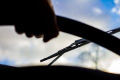 Dirty scratched car windshield with wiper through blurred steering wheel with driver`s hand on blurred background royalty free stock images Dirty scratched car windshield with wiper through blurred steering wheel with driver`s hand on blurred background royalty free stock images