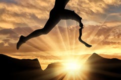 Disabled athlete with prosthetic leg jumping across rock on sunset royalty free stock photography Disabled athlete with prosthetic leg jumping across rock on sunset royalty free stock photography