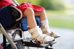 Disabled girl sitting in wheelchair. On her legs orthosis. Child cerebral palsy. Inclusion