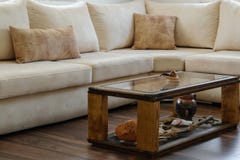 Diseño interior casero - sofá contemporáneo cómodo en colores naturales y una tabla de madera con los objetos antiguos imagen de archivo Diseño interior casero - sofá contemporáneo cómodo en colores naturales y una tabla de madera con los objetos antiguos imagen de archivo