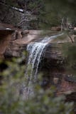 Distant View of Water Falling Over Red Sandstone Cliffs with Branches in Winter royalty free stock images Distant View of Water Falling Over Red Sandstone Cliffs with Branches in Winter royalty free stock images
