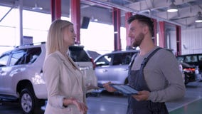 Distributore di benzina, ragazza felice del cliente e meccanico parlanti della manutenzione dell'automobile all'officina riparazi video d archivio Distributore di benzina, ragazza felice del cliente e meccanico parlanti della manutenzione dell'automobile all'officina riparazi video d archivio
