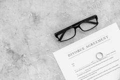 Divorce agreement. Wedding ring on document on grey background top view copy space Stock Photos Divorce agreement. Wedding ring on document on grey background top view copy space Stock Photos