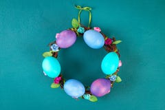 Diy påskkrans av ris, målade ägg och konstgjorda blommor på en grön bakgrund arkivfoton Diy påskkrans av ris, målade ägg och konstgjorda blommor på en grön bakgrund arkivfoton