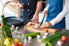 Dobiera się w miłości, wydaje czas w kuchennym kucharstwie wpólnie, coś dziewczyn cięć pieczarki zdjęcie stock Dobiera się w miłości, wydaje czas w kuchennym kucharstwie wpólnie, coś dziewczyn cięć pieczarki zdjęcie stock