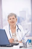 Docteur aîné travaillant au bureau photographie stock Docteur aîné travaillant au bureau photographie stock