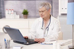 Docteur aîné travaillant au bureau image libre de droits Docteur aîné travaillant au bureau image libre de droits