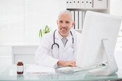 Docteur heureux dactylographiant sur le clavier photo libre de droits Docteur heureux dactylographiant sur le clavier photo libre de droits