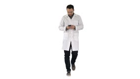 Docteur marchant et ?crivant un message au t?l?phone sur le fond blanc photo libre de droits Docteur marchant et ?crivant un message au t?l?phone sur le fond blanc photo libre de droits