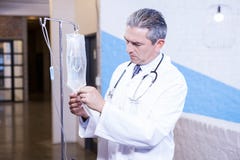 Docteur masculin vérifiant une perfusion de sérum physiologique images stock Docteur masculin vérifiant une perfusion de sérum physiologique images stock