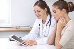 Doctor And Patient Sitting At The Desk. The Physician Or Therapist Makes A Diagnosis. Health Care, Medicine And Patie Stock Photo