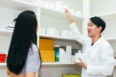 Doctor asiático del farmacéutico en vestido profesional que explica y que da consejo con el cliente femenino en tienda de la drog imagenes de archivo Doctor asiático del farmacéutico en vestido profesional que explica y que da consejo con el cliente femenino en tienda de la drog imagenes de archivo