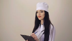 Doctor bastante de sexo femenino que sonríe y que anota en el fondo 4K metrajes Doctor bastante de sexo femenino que sonríe y que anota en el fondo 4K metrajes