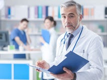 Doctor confiado que comprueba informes médicos fotos de archivo Doctor confiado que comprueba informes médicos fotos de archivo