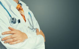 Doctor Crosses His Arms Over His Chest on grey background. Health care Medicine Concept royalty free stock photo Doctor Crosses His Arms Over His Chest on grey background. Health care Medicine Concept royalty free stock photo