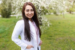 Doctor de sexo femenino al aire libre de un hospital en jard?n de flores espacio de la copia del fondo m?dico Mujer joven alegre fotos de archivo Doctor de sexo femenino al aire libre de un hospital en jard?n de flores espacio de la copia del fondo m?dico Mujer joven alegre fotos de archivo