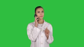 Doctor de sexo femenino sonriente en el teléfono que habla mientras que camina en una pantalla verde, llave de la croma metrajes Doctor de sexo femenino sonriente en el teléfono que habla mientras que camina en una pantalla verde, llave de la croma metrajes