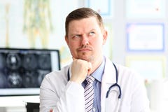 Doctor de sexo masculino con la expresión facial extraña sentarse en su oficina fotos de archivo Doctor de sexo masculino con la expresión facial extraña sentarse en su oficina fotos de archivo