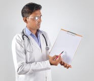 Doctor de sexo masculino en la escritura del uniforme del blanco en el papel del tablero fotos de archivo libres de regalías Doctor de sexo masculino en la escritura del uniforme del blanco en el papel del tablero fotos de archivo libres de regalías